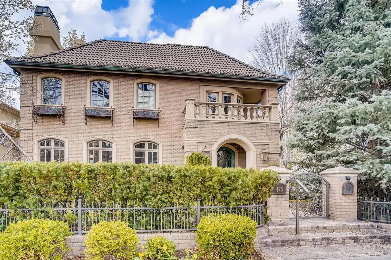 A stone residence behind an iron fence and hedge at 475 Madison Street in Cherry Creek, one of our past sales